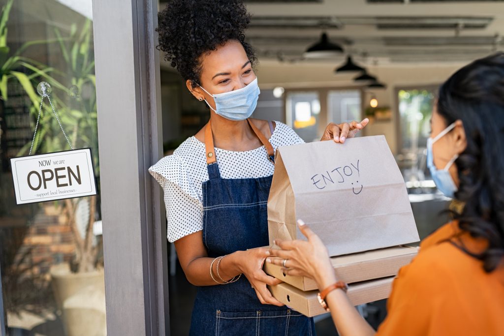 Shop local promotion with lady in face mask handing over a bag